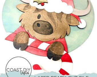 Könnte beinhalten: Weihnachtsschmuck aus Holz mit einem Highland-Rind, das einen Weihnachtsmannhut und einen rot-weiß gestreiften Schal trägt. Der Schmuck hat einen hellblauen Hintergrund und den Text "COAST DIY Digital" und "LASER READY CUT FILE".