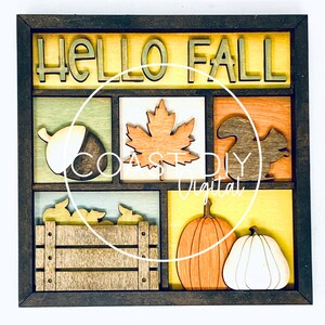 May include: A wooden framed wall decor with the words "Hello Fall" in a yellow, orange, and brown color scheme. The frame contains six squares with various fall-themed images, including an acorn, a maple leaf, a squirrel, a pumpkin, a bushel of leaves, and a pumpkin.