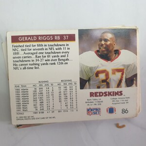 May include: A vintage football trading card featuring Gerald Riggs, a running back for the Washington Redskins. The card is red, white, and blue with the team logo and Riggs's number 37. The card includes Riggs's career statistics and biographical information.