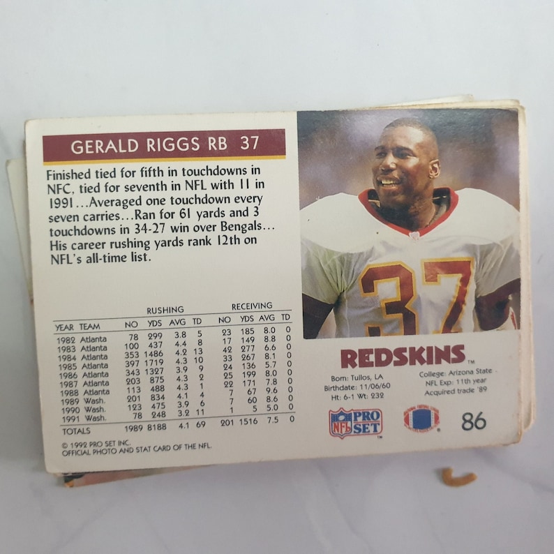 May include: A vintage football trading card featuring Gerald Riggs, a running back for the Washington Redskins. The card is red, white, and blue with the team logo and Riggs's number 37. The card includes Riggs's career statistics and biographical information.