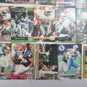 May include: A collection of 11 trading cards featuring NFL players from the 1990s. The cards are in various colors, including red, blue, green, and white. The cards feature players from teams such as the Detroit Lions, the Houston Oilers, and the Buffalo Bills. The cards are in good condition and would be a great addition to any sports card collection.