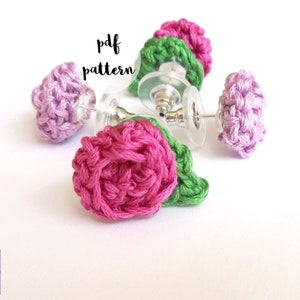 May include: Three pairs of crocheted flower earrings in pink, purple, and green. The earrings are attached to silver posts.