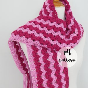 Puede incluir: Bufanda de ganchillo hecha a mano en tonos rosa y magenta, exhibida en un maniquí. La bufanda presenta un patrón de chevrón y flecos. El texto "pdf pattern" es visible en la bufanda.