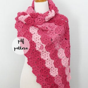Könnte beinhalten: Ein rosa und hellrosa gehäkeltes Tuch mit einem gewellten Rand. Das Tuch ist über eine weiße Schaufensterpuppe gelegt. Der Text "pdf pattern" ist in einem weißen Kreis auf dem Bild geschrieben. Der Text "fiber flux" ist in einem grauen Kreis auf dem Bild geschrieben.