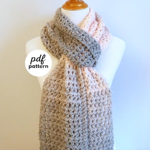 Puede incluir: Una bufanda de ganchillo hecha a mano en tonos grises y rosas, colocada sobre un maniquí. La bufanda presenta un patrón de puntada abierto y calado. La imagen incluye el texto "pdf pattern" y "fiber flux".