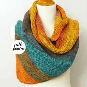 May include: A multi-coloured knitted cowl scarf in shades of orange, teal, and brown, displayed on a mannequin. The scarf has a striped pattern and is made of soft yarn. The text "pdf pattern" is visible on the scarf.