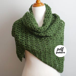 May include: A green crocheted shawl displayed on a mannequin. The shawl is triangular, with a cowl neck and open weave. The image includes a white circle with the text "pdf pattern".