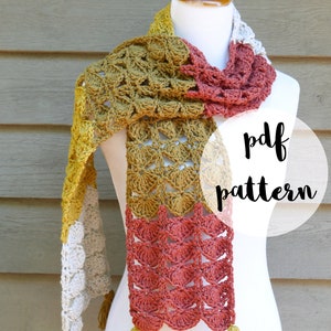 May include: A crocheted scarf with a multi-coloured pattern of mustard yellow, beige, and coral. The scarf has tassels on each end and is displayed on a white mannequin. The text "pdf pattern" and "fiber flux" are visible in the image.