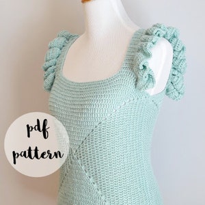 May include: A crochet top with a light blue color and a diamond pattern. The top has a ruffled neckline and straps. The text "pdf pattern" is visible in the image.
