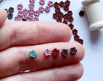 May include: Assortment of small flower-shaped metal buttons in pink, red, blue, and black.