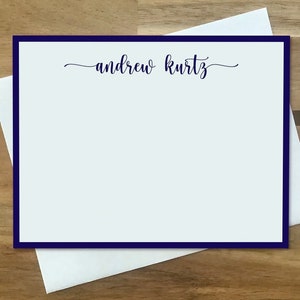 May include: A white card with a navy blue border and the text "andrew kurtz" in cursive script.