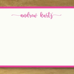 May include: A white card with a pink border and the name "andrew kurtz" written in pink cursive.