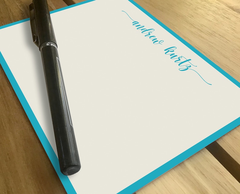 May include: A white card with a turquoise border and the name "andrew kurtz" written in turquoise cursive.