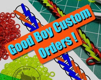 May include: A close-up of a colorful rubber band bracelet with a pattern of red, blue, and orange bands. The bracelet is on a white sheet of paper with a diagram of the bracelet pattern. The image also includes a pile of red rubber bands, a pile of green rubber bands, and a sign that says "Good Boy Custom Orders!" in orange and blue letters.