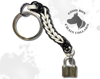 May include: Black and white chain keychain with a silver padlock and a silver key ring. The chain is made of two colors of metal, black and white. The keychain has a tag that says "Good Boy Chain Collars".