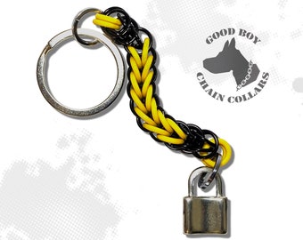 May include: A keychain with a silver key ring and a chain made of yellow and black metal rings. A small silver padlock hangs from the chain. The text "GOOD BOY CHAIN COLLARS" is in the upper right corner.