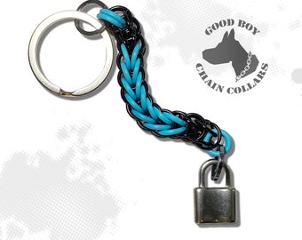 May include: A black and turquoise chain keychain with a silver padlock charm. The keychain has a silver ring for attaching keys. The keychain is labeled "Good Boy Chain Collars".