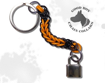 May include: A black and orange chain keychain with a silver padlock and a silver key ring. The keychain has the text "GOOD BOY CHAIN COLLARS" on a circular tag.