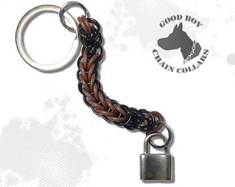 May include: A brown and black chain keychain with a silver padlock attached. The chain is made of metal and leather. The keychain has a silver ring for attaching keys. The keychain has a logo that says "Good Boy Chain Collars".