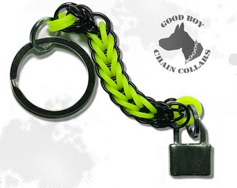 May include: Black and neon green chain keychain with a silver padlock and a key ring. The keychain has the text "GOOD BOY CHAIN COLLARS" on a black and white dog silhouette.