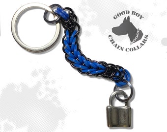 May include: A blue and black chain keychain with a silver padlock charm. The keychain has a silver key ring and the chain is made of woven paracord. The keychain has a logo that says "Good Boy Chain Collars".