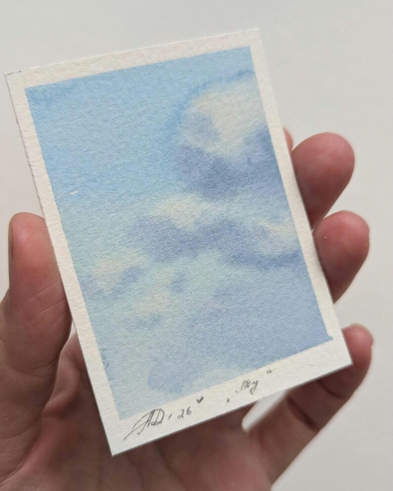 Pu&ograve; includere: Un piccolo acquerello di un cielo blu con nuvole bianche. L'opera d'arte &egrave; firmata e datata "AD, 26" con la parola "Sky" scritta accanto. Il dipinto &egrave; tenuto in una mano.