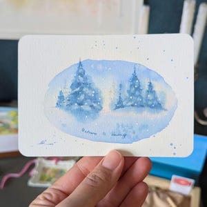 Postal original en acuarela con paisaje nevado con abetos y pinos