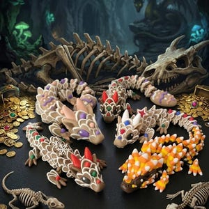 Puede incluir: Cuatro figuras de dragón hechas para parecer galletas de jengibre, decoradas con glaseado de colores, dulces y escamas de maíz dulce. Los dragones están dispuestos entre monedas de oro esparcidas, restos esqueléticos y un cráneo de dragón.