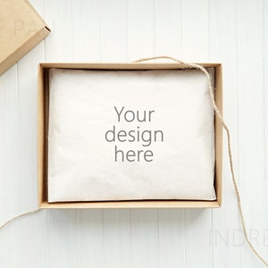 May include: A brown cardboard box with a white tissue paper liner and twine tied around it. The tissue paper has the text "Your design here" printed on it.