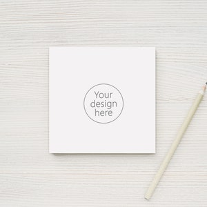 May include: A white blank card with the text "Your design here" inside a circle on a white wooden surface with a wooden pencil beside it.