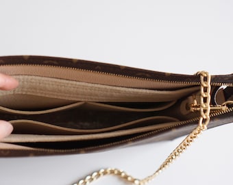 May include: A brown and beige monogrammed purse with a gold chain strap. The purse is open and shows three interior pockets.