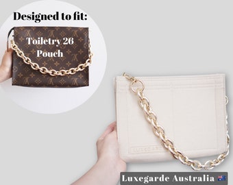 May include: A white canvas bag with a gold chain strap. The bag is designed to fit a Louis Vuitton Toiletry 26 Pouch. The bag is made by Luxegarde Australia.