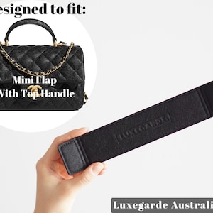 Puede incluir: Bolso de mano acolchado negro con una correa de cadena dorada y un asa superior. El bolso tiene el texto "Mini Flap With Top Handle" en la parte delantera.