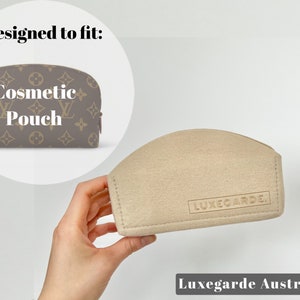 May include: Beige felt pouch with the text "Luxegarde" embossed on the front. Designed to fit a brown and beige cosmetic pouch with the text "Cosmetic Pouch" printed on the front.