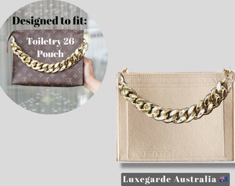 May include: Beige felt bag insert with a gold chain handle. The insert is designed to fit the Louis Vuitton Toiletry 26 Pouch. The insert has the text "Luxegarde Australia" printed on the bottom.