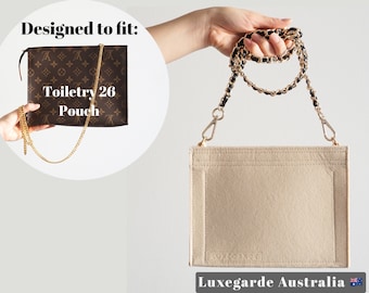 May include: Beige felt bag insert with a gold chain strap. The bag insert is designed to fit the Louis Vuitton Toiletry 26 Pouch. The bag insert has the text "Luxegarde Australia" printed on the bottom.