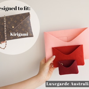 Puede incluir: Tres organizadores de fieltro estilo sobre en rosa, rojo y burdeos. Los organizadores están diseñados para caber dentro de un bolso de diseño marrón y dorado etiquetado como "kirigami".