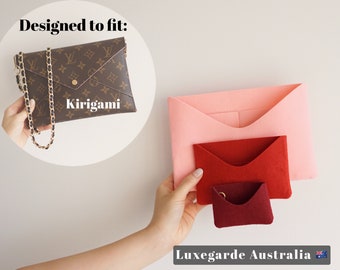 May include: Three felt envelope-style organizers in pink, red, and burgundy. The organizers are designed to fit inside a brown and gold designer handbag labeled "kirigami".