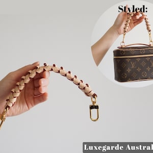 May include: A braided leather strap with gold hardware. The strap is designed to be used as a replacement handle for a handbag. The strap is shown in a hand, and the image also shows a brown and tan handbag with the strap attached.