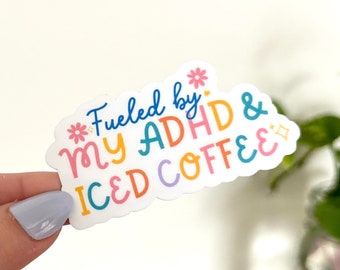 Pode incluir: Um adesivo branco com uma fonte colorida e caprichosa que diz "Fueled by my ADHD & Iced Coffee".