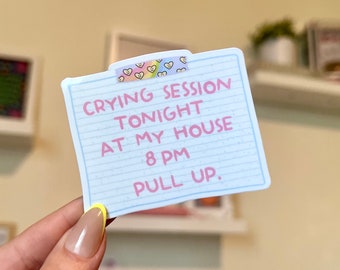 May include: A blue and white lined note with pink text that reads "Crying Session Tonight at My House 8 PM Pull Up." The note is decorated with a pink and white washi tape with hearts.