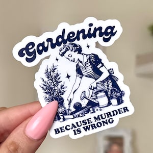 May include: A white sticker with a blue illustration of a woman gardening. The text "Gardening because murder is wrong" is printed on the sticker.