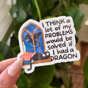 Pode incluir: Um autocolante extravagante com um dragão e um gato. O autocolante tem o texto: "I THINK a lot of my PROBLEMS would be solved if I had a DRAGON." O dragão é preto e o gato é preto.