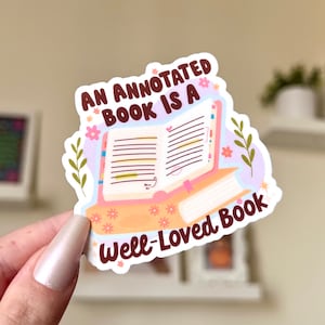 May include: A sticker with an illustrated open book with colorful flowers and the text "An annotated book is a well-loved book."