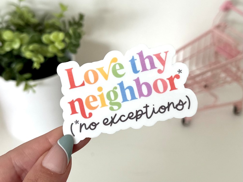 Może przedstawiać: Biała naklejka z napisem "Love thy neighbor" w tęczowych kolorach. Poniżej gł&oacute;wnego tekstu znajduje się fraza "(*no exceptions)" w kolorze czarnym. Naklejka jest trzymana przez osobę.