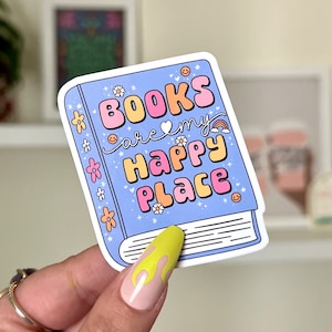 May include: A blue book sticker with the text "Books are my happy place" in colorful, bubbly letters. The sticker features a rainbow, flowers, and smiley faces.