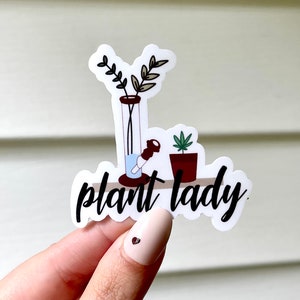 May include: White sticker with a black and white illustration of a bong, a potted plant, and the text "plant lady".