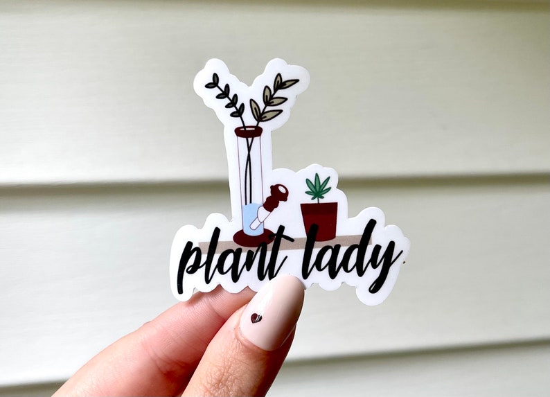 May include: White sticker with a black and white illustration of a bong, a potted plant, and the text "plant lady".