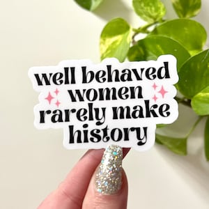 May include: White sticker with black text that reads "well behaved women rarely make history". The text is in a retro font style. There are two pink stars on either side of the word "women".