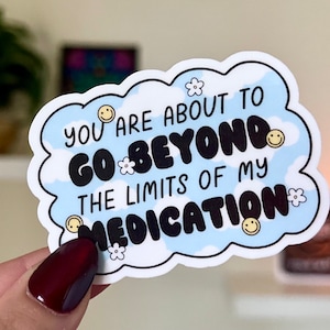 May include: A white sticker with a blue cloud design and the text "You are about to go beyond the limits of my medication" in black. The cloud has white flowers and yellow smiley faces.